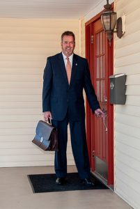 Robert Campbell standing at his door with a briefcase in hand.